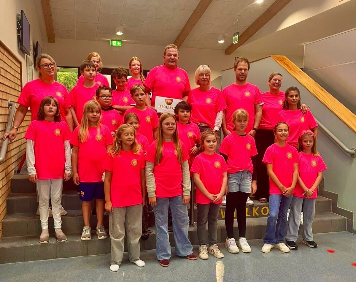 Gruppenfoto von Kindern und Erwachsenen in neuen Trikots.